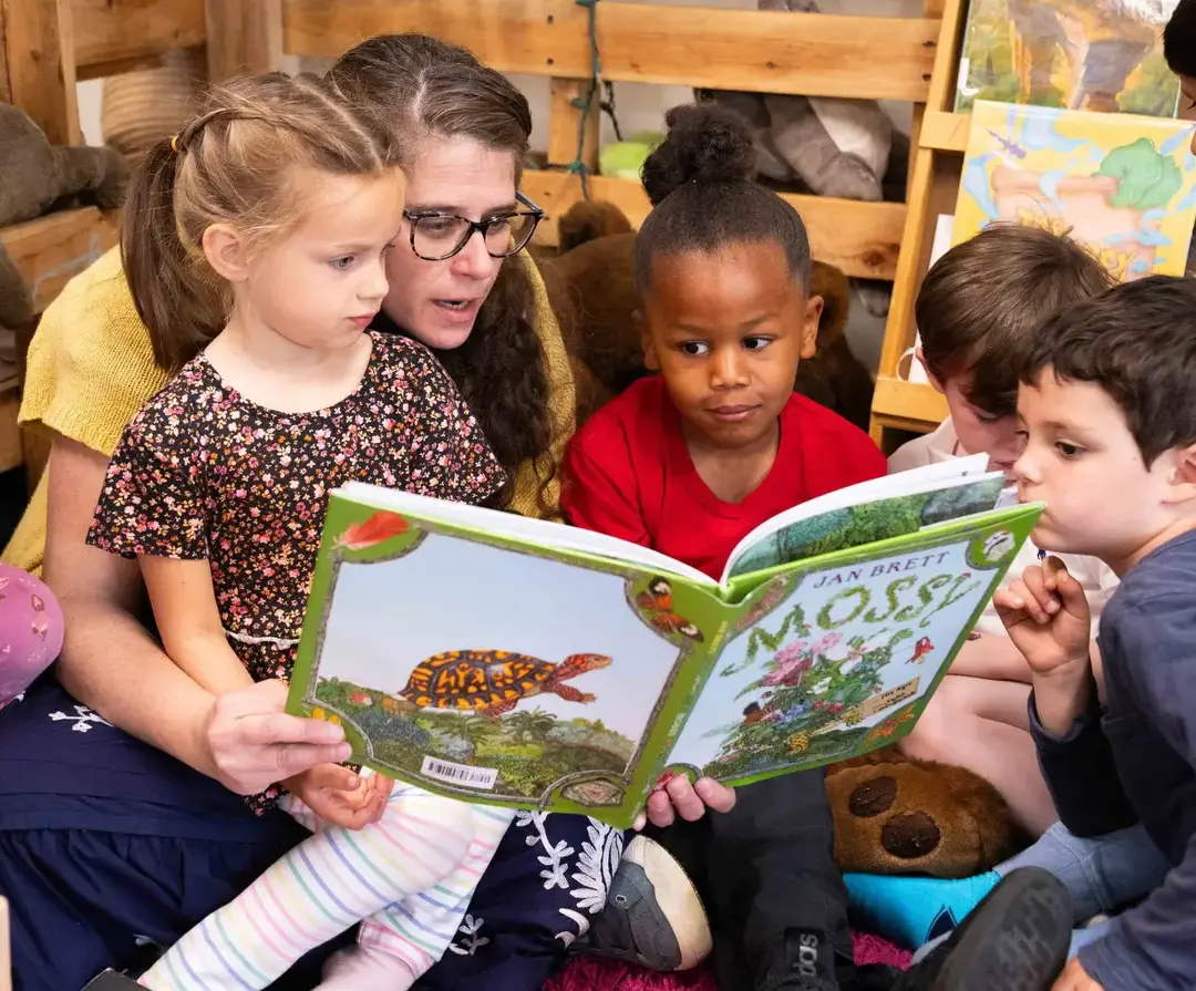 King School teacher and PreK students reading a book together